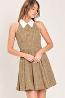 Woman wearing a hazel tweed mini dress featuring halter neckline with white collar finish, front button detail, full circle skirt and back zipper closure background | Flying Tomato