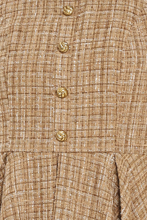 Woman wearing a hazel tweed mini dress featuring halter neckline with white collar finish, front button detail, full circle skirt and back zipper closure background | Flying Tomato