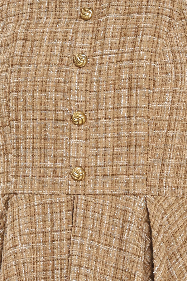Woman wearing a hazel tweed mini dress featuring halter neckline with white collar finish, front button detail, full circle skirt and back zipper closure background | Flying Tomato