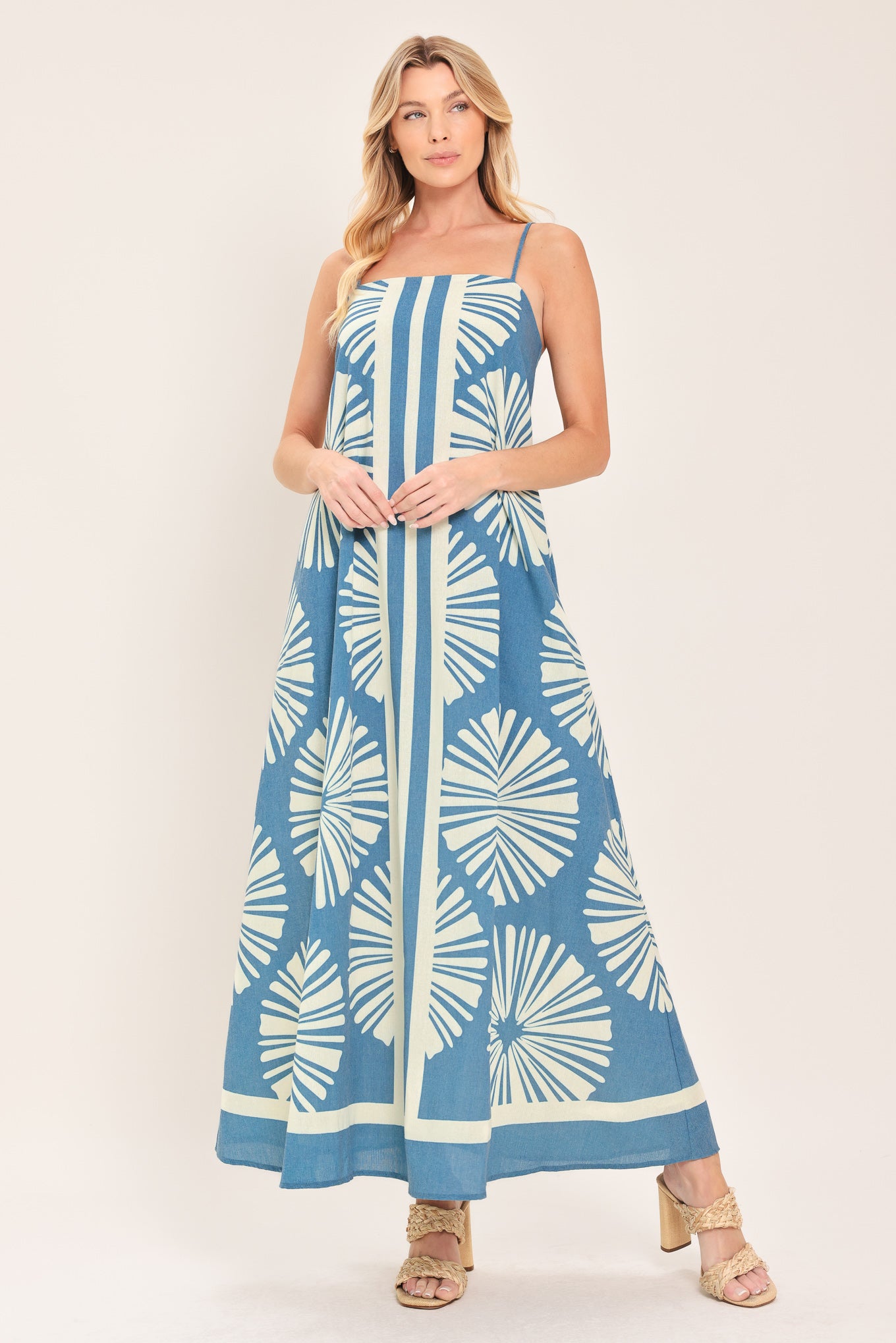 Woman wearing a blue and white patterned maxi dress featuring straight neckline, straps and bare back with zipper closure | Flying Tomato