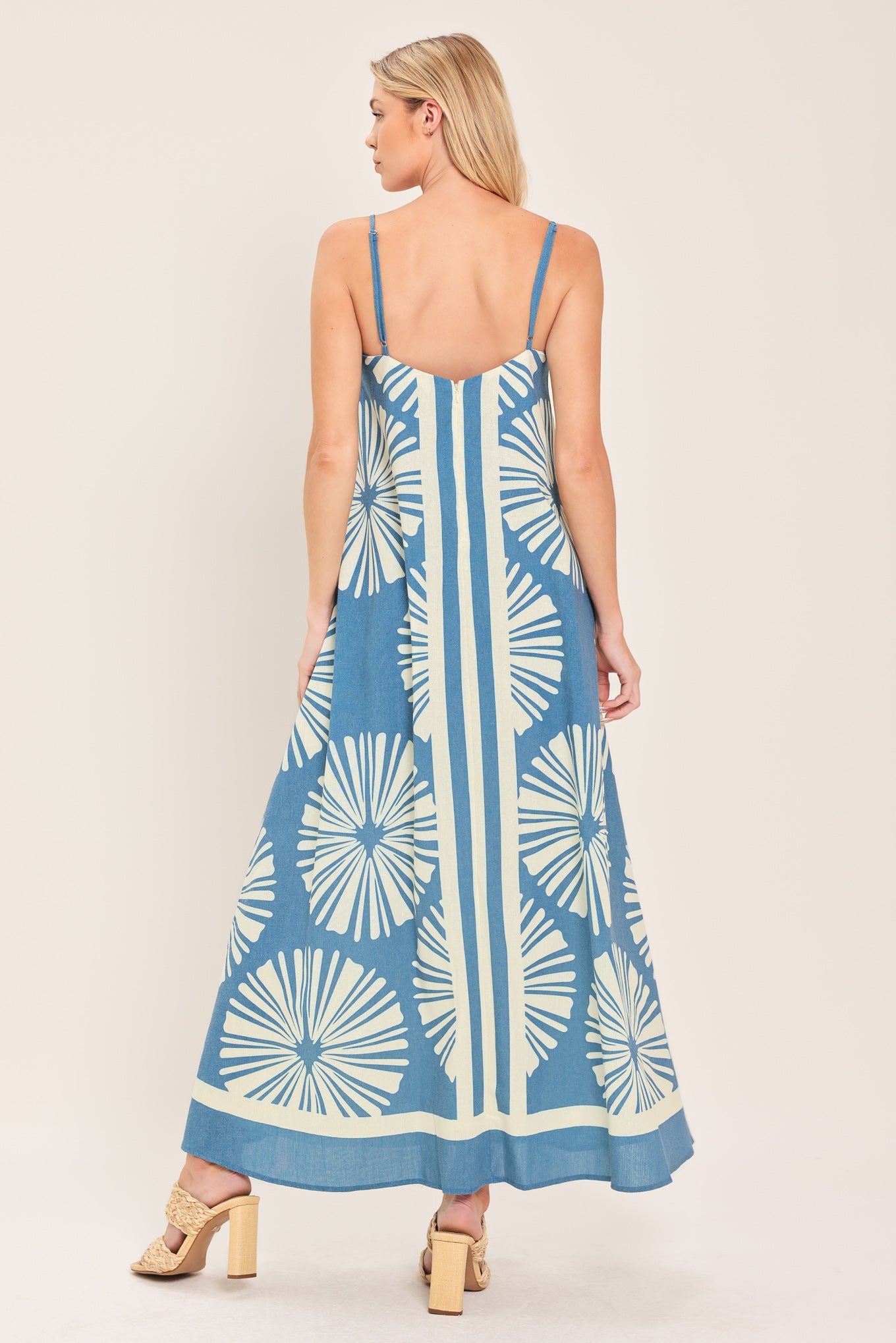 Woman wearing a blue and white patterned maxi dress featuring straight neckline, straps and bare back with zipper closure | Flying Tomato