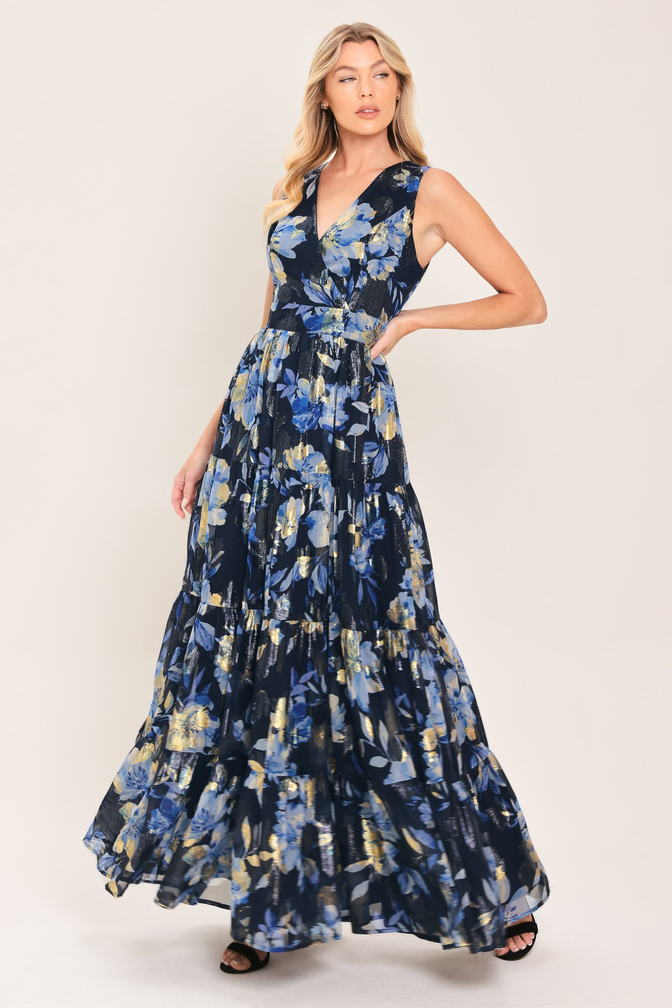 Woman wearing a navy blue and gold floral printed jacquard woven maxi dress featuring surplice neckline, sleeveless, tier skirt and back zipper closure | Flying Tomato