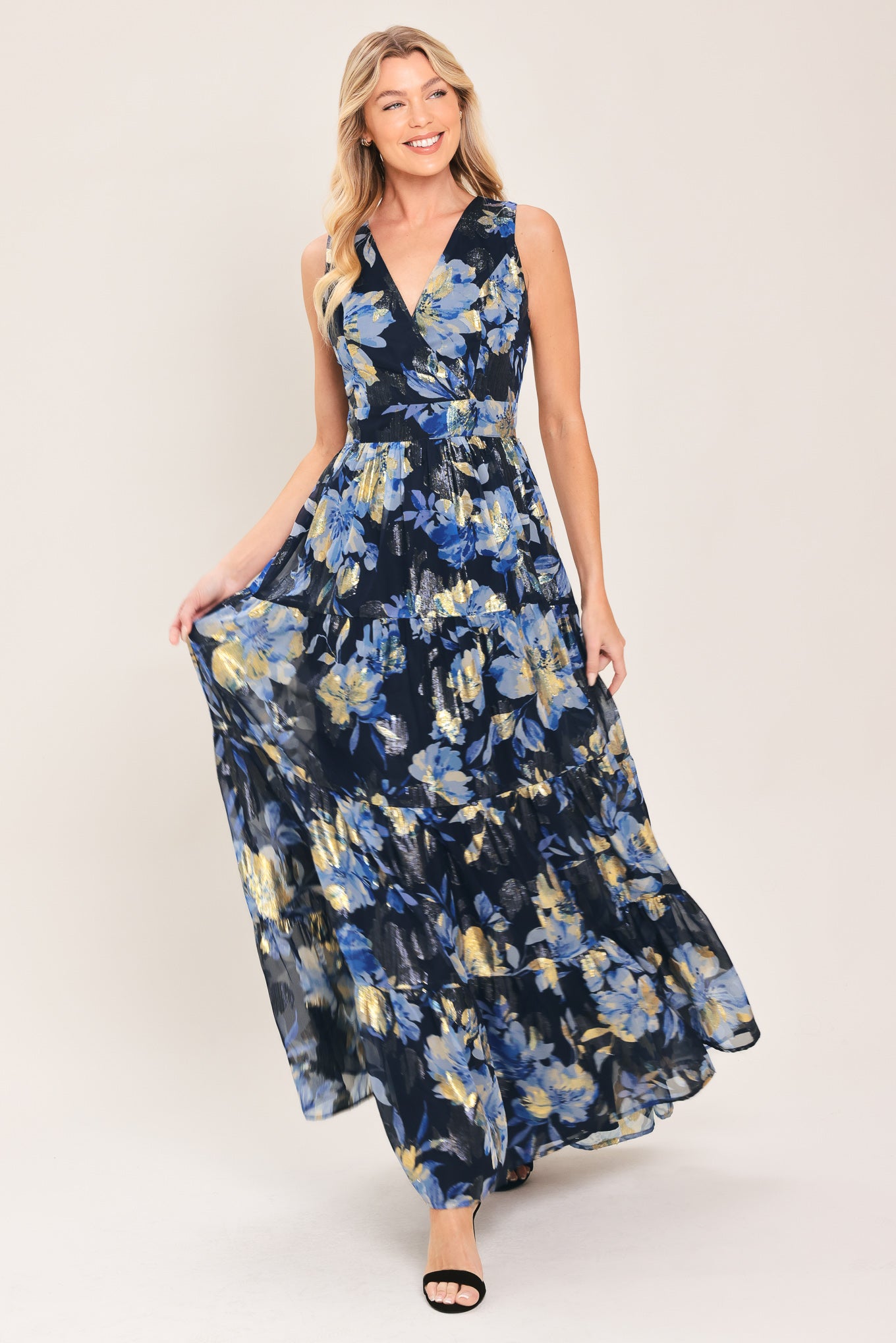 Woman wearing a navy blue and gold floral printed jacquard woven maxi dress featuring surplice neckline, sleeveless, tier skirt and back zipper closure | Flying Tomato
