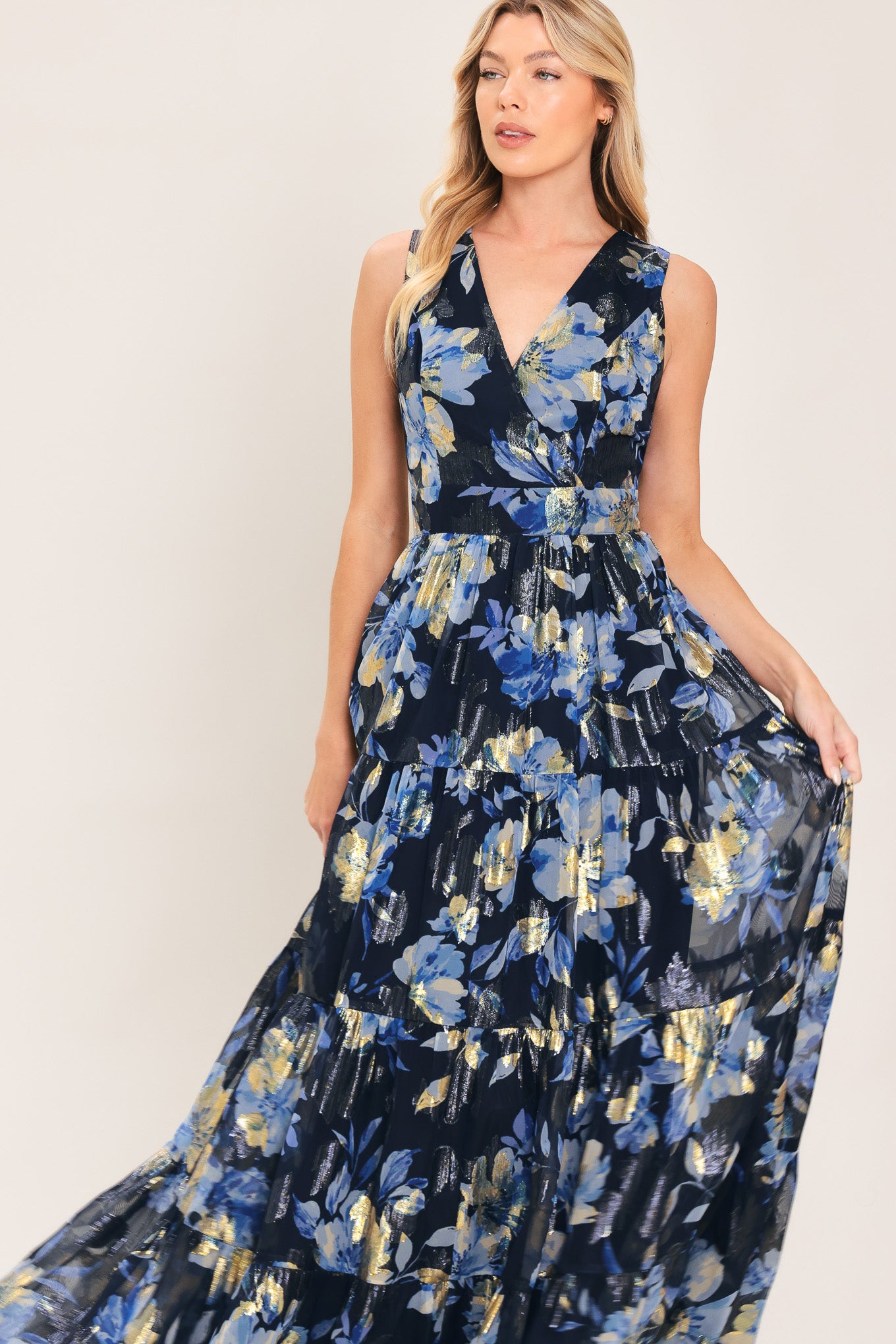 Woman wearing a navy blue and gold floral printed jacquard woven maxi dress featuring surplice neckline, sleeveless, tier skirt and back zipper closure | Flying Tomato