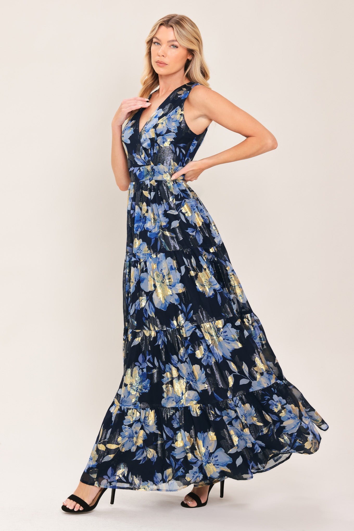 Woman wearing a navy blue and gold floral printed jacquard woven maxi dress featuring surplice neckline, sleeveless, tier skirt and back zipper closure | Flying Tomato
