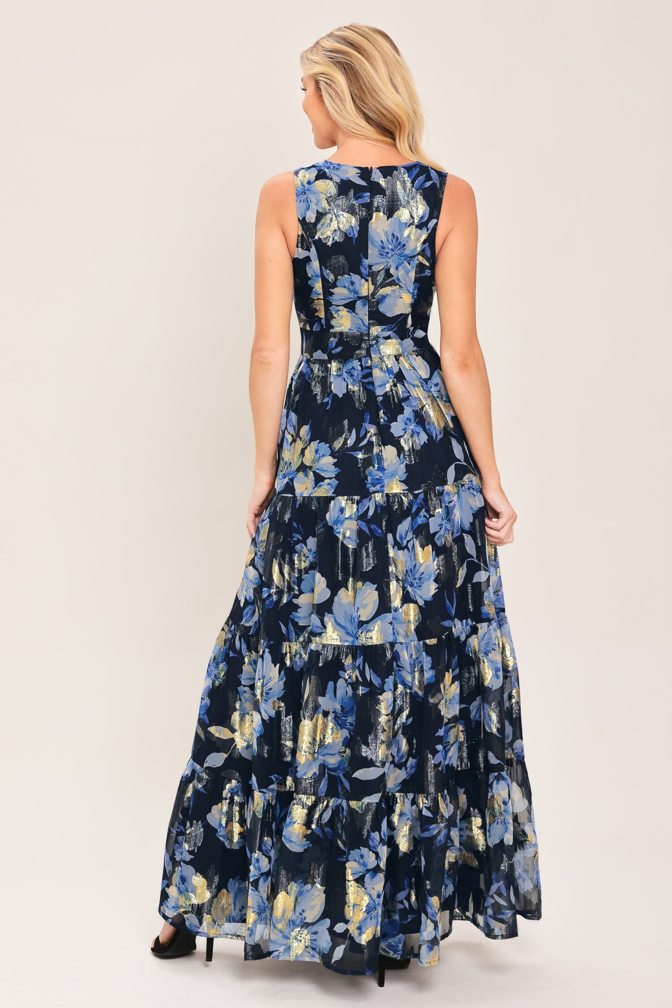 Woman wearing a navy blue and gold floral printed jacquard woven maxi dress featuring surplice neckline, sleeveless, tier skirt and back zipper closure | Flying Tomato