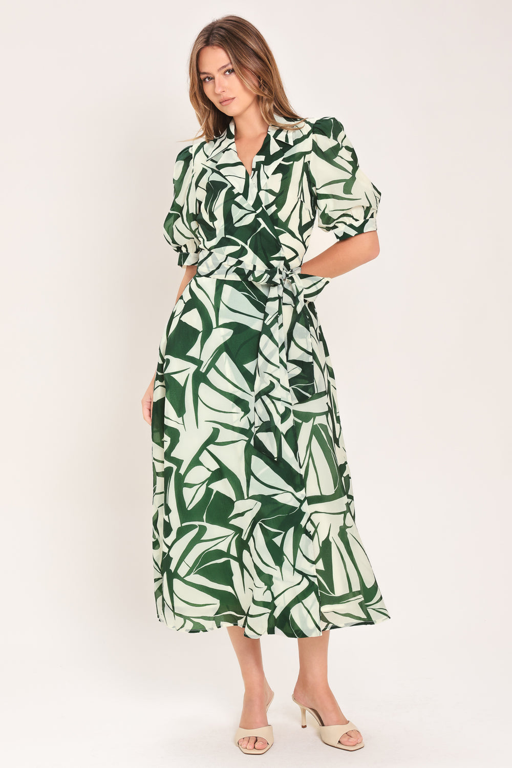 Woman wearing an green and ivory leaf-patterned true wrap midi dress featuring collar, puff short sleeve and full skirt | Flying Tomato