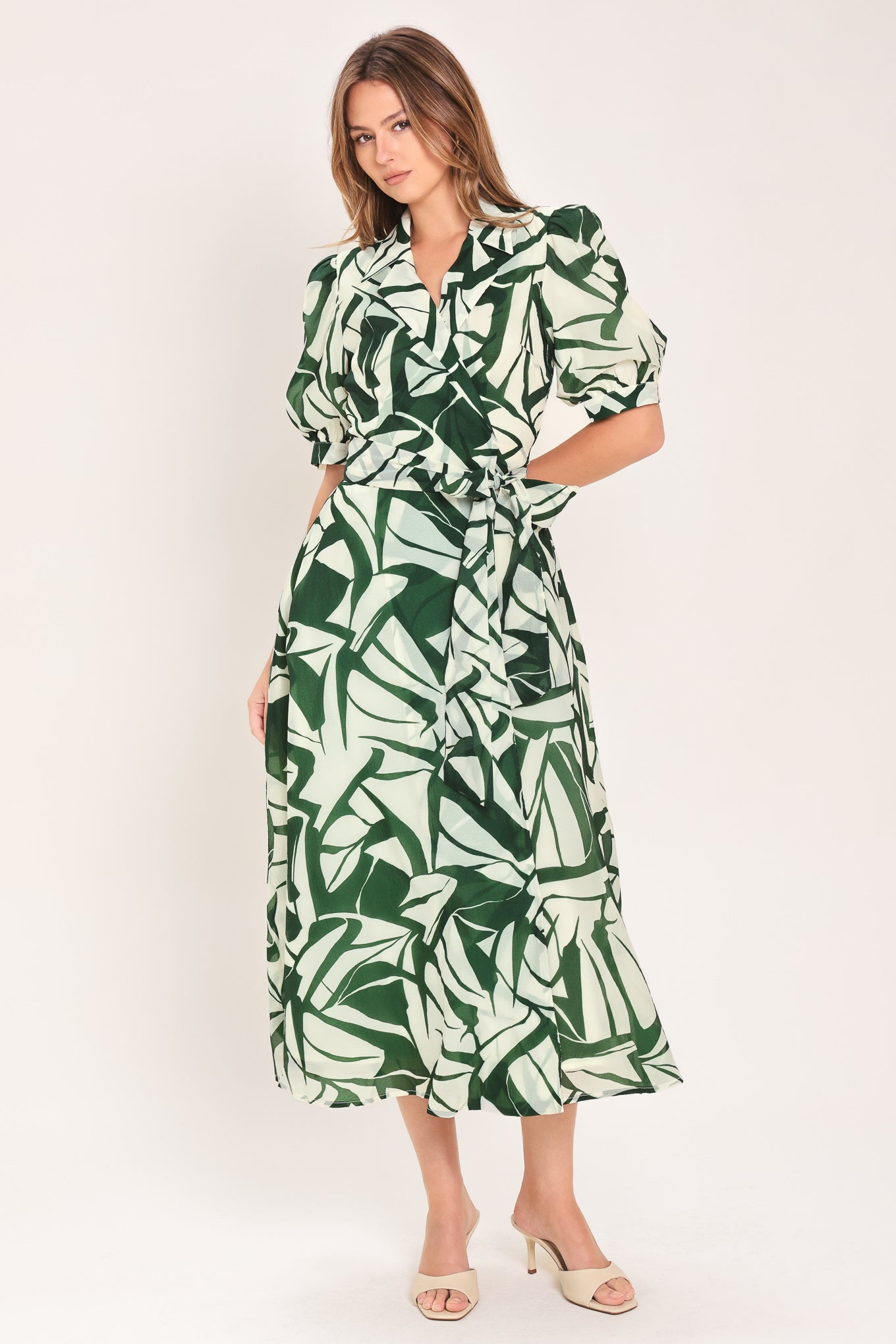 Woman wearing an green and ivory leaf-patterned true wrap midi dress featuring collar, puff short sleeve and full skirt | Flying Tomato