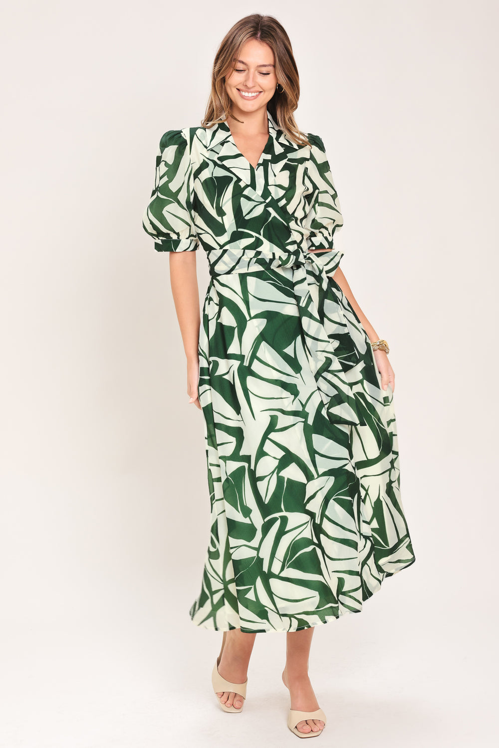 Woman wearing an green and ivory leaf-patterned true wrap midi dress featuring collar, puff short sleeve and full skirt | Flying Tomato
