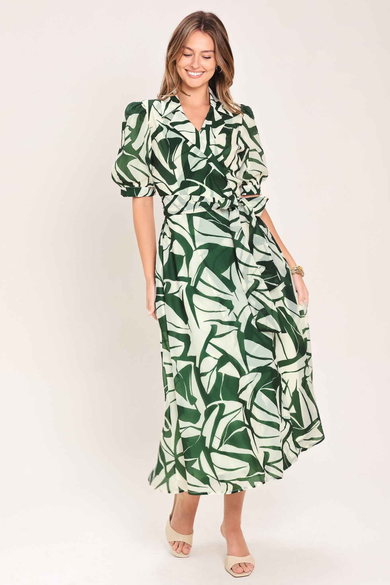 Woman wearing an green and ivory leaf-patterned true wrap midi dress featuring collar, puff short sleeve and full skirt | Flying Tomato