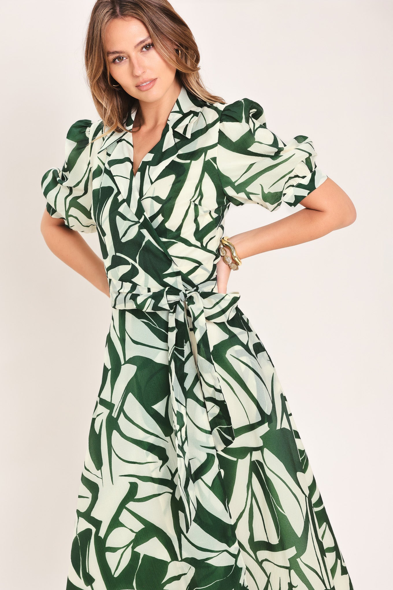 Woman wearing an green and ivory leaf-patterned true wrap midi dress featuring collar, puff short sleeve and full skirt | Flying Tomato