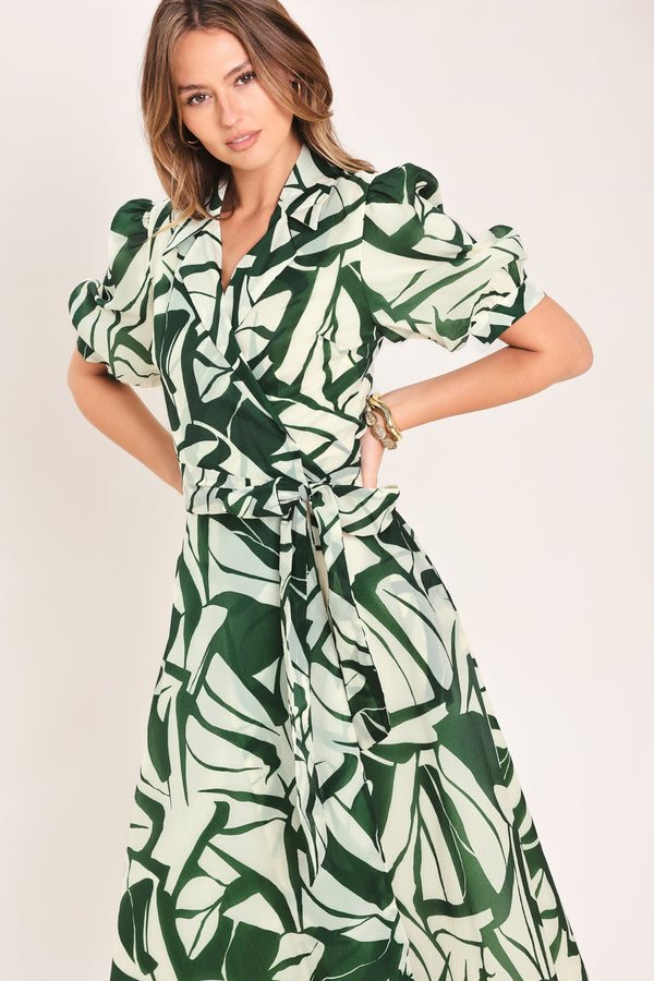 Woman wearing an green and ivory leaf-patterned true wrap midi dress featuring collar, puff short sleeve and full skirt | Flying Tomato
