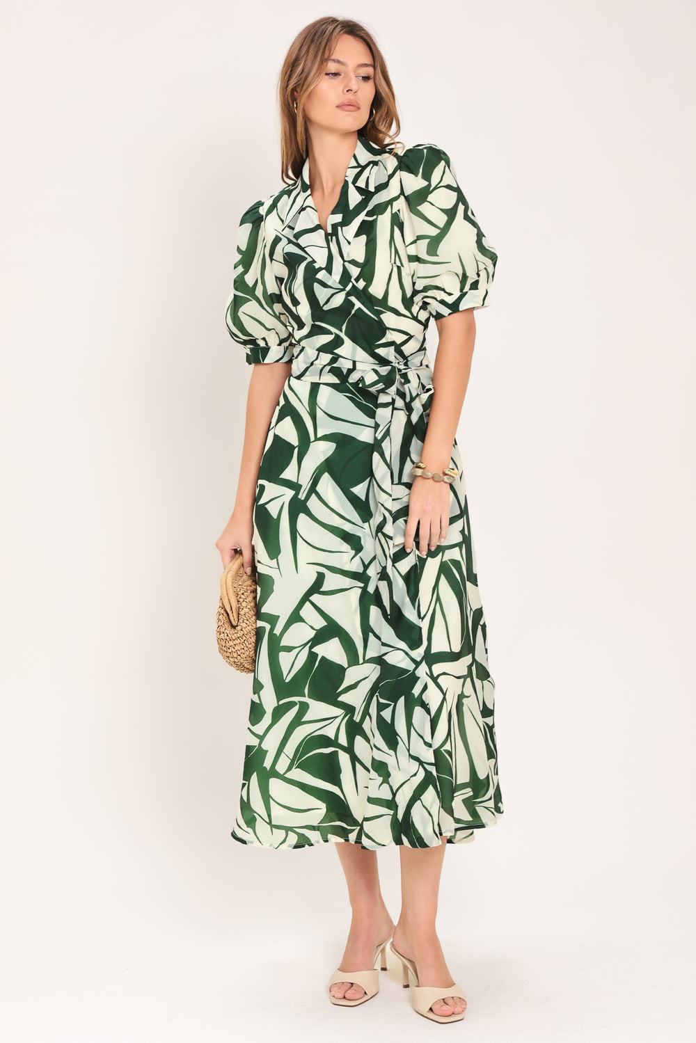 Woman wearing an green and ivory leaf-patterned true wrap midi dress featuring collar, puff short sleeve and full skirt | Flying Tomato
