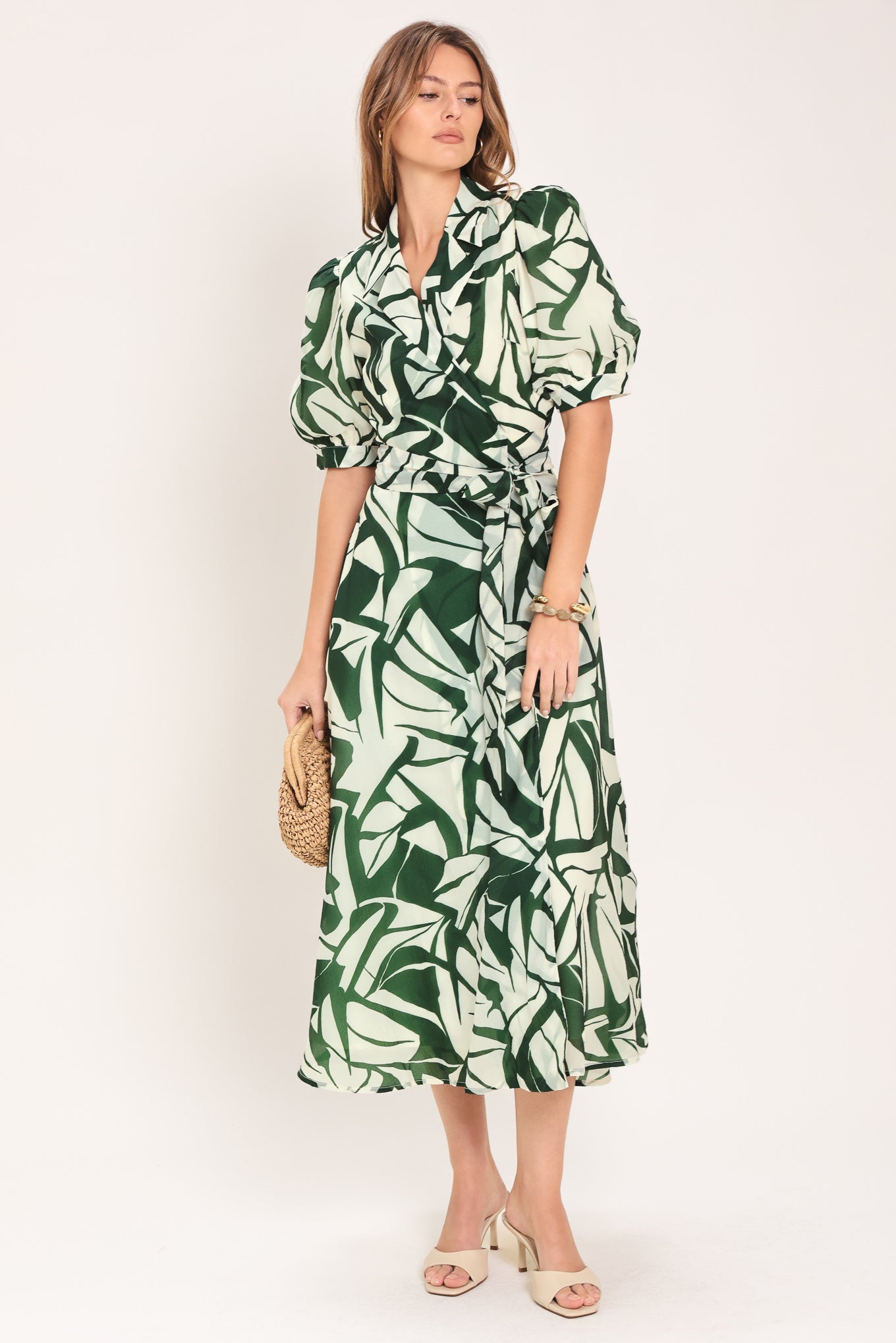 Woman wearing an green and ivory leaf-patterned true wrap midi dress featuring collar, puff short sleeve and full skirt | Flying Tomato