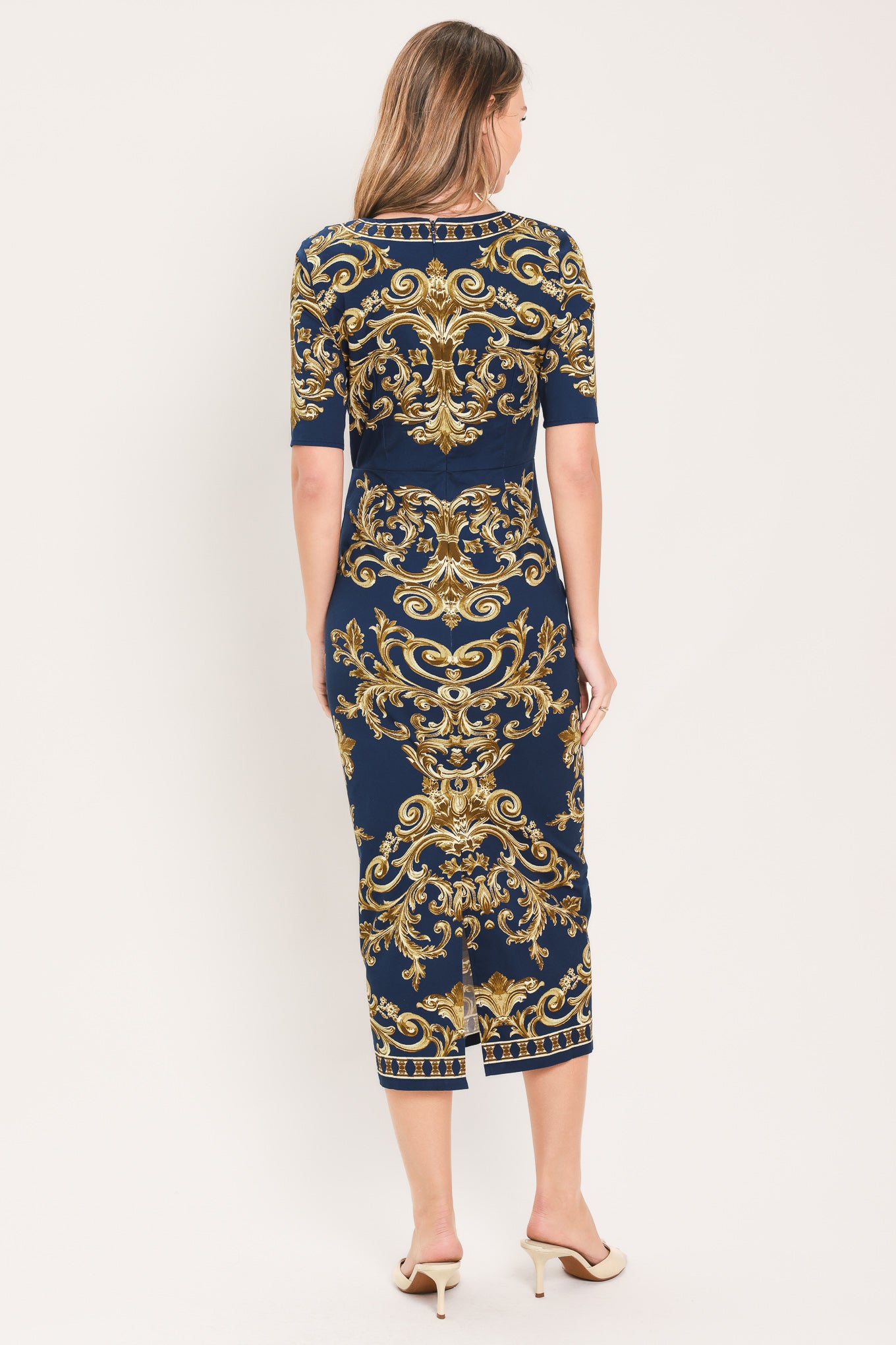 A woman wearing a navy blue midi dress with an ornate gold baroque pattern, featuring short sleeves and a crew neck | Flying Tomato