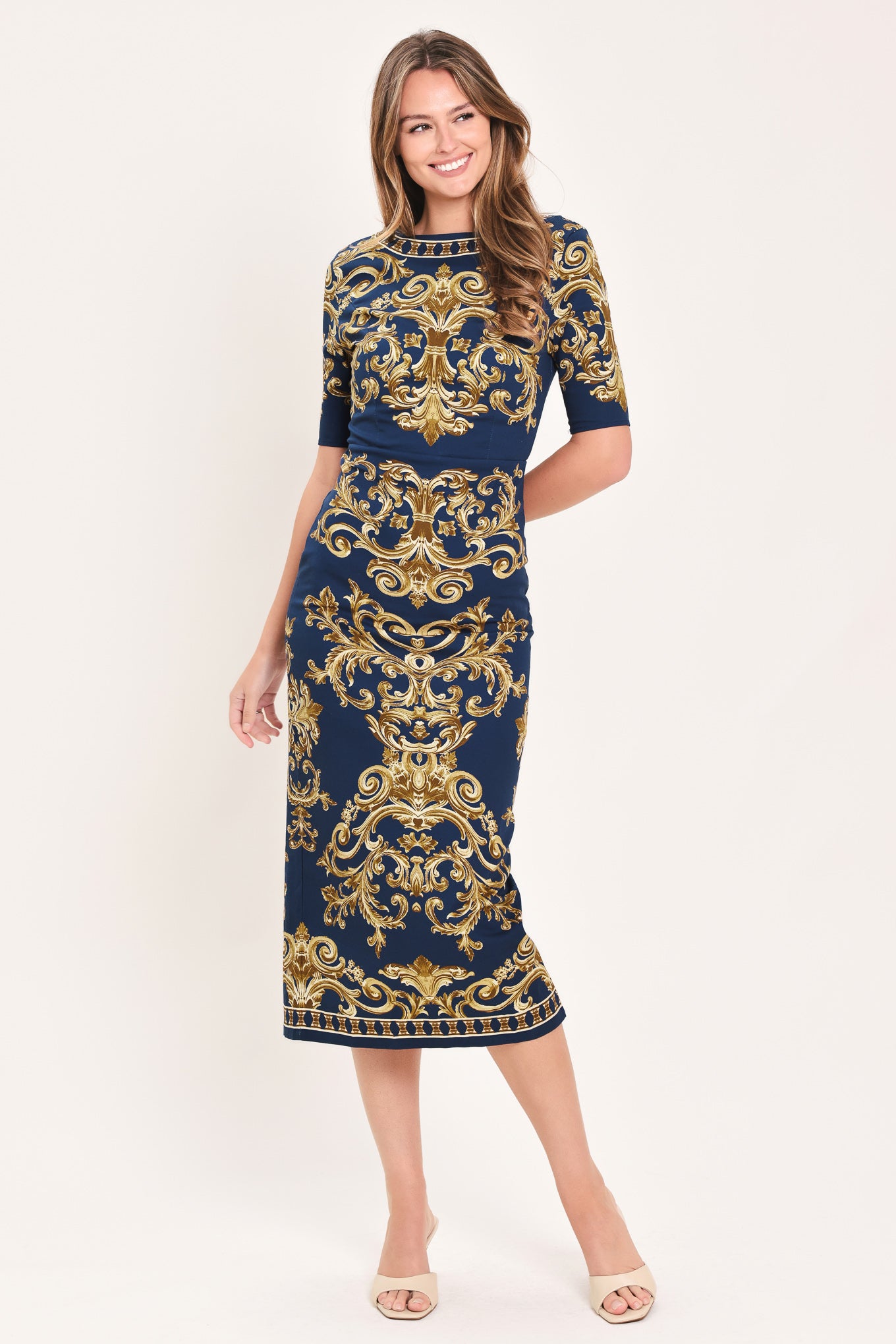 A woman wearing a navy blue midi dress with an ornate gold baroque pattern, featuring short sleeves and a crew neck | Flying Tomato