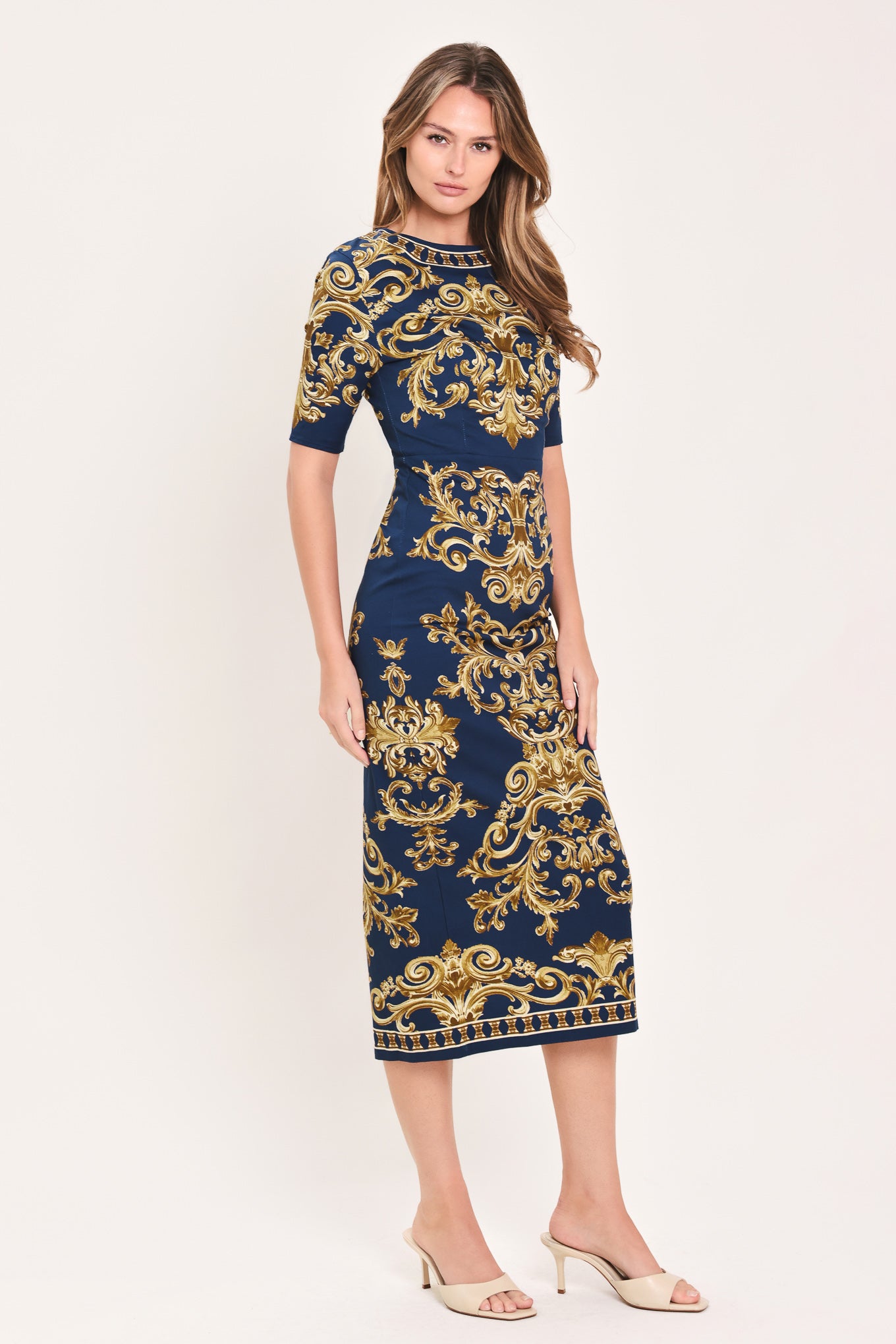 A woman wearing a navy blue midi dress with an ornate gold baroque pattern, featuring short sleeves and a crew neck | Flying Tomato