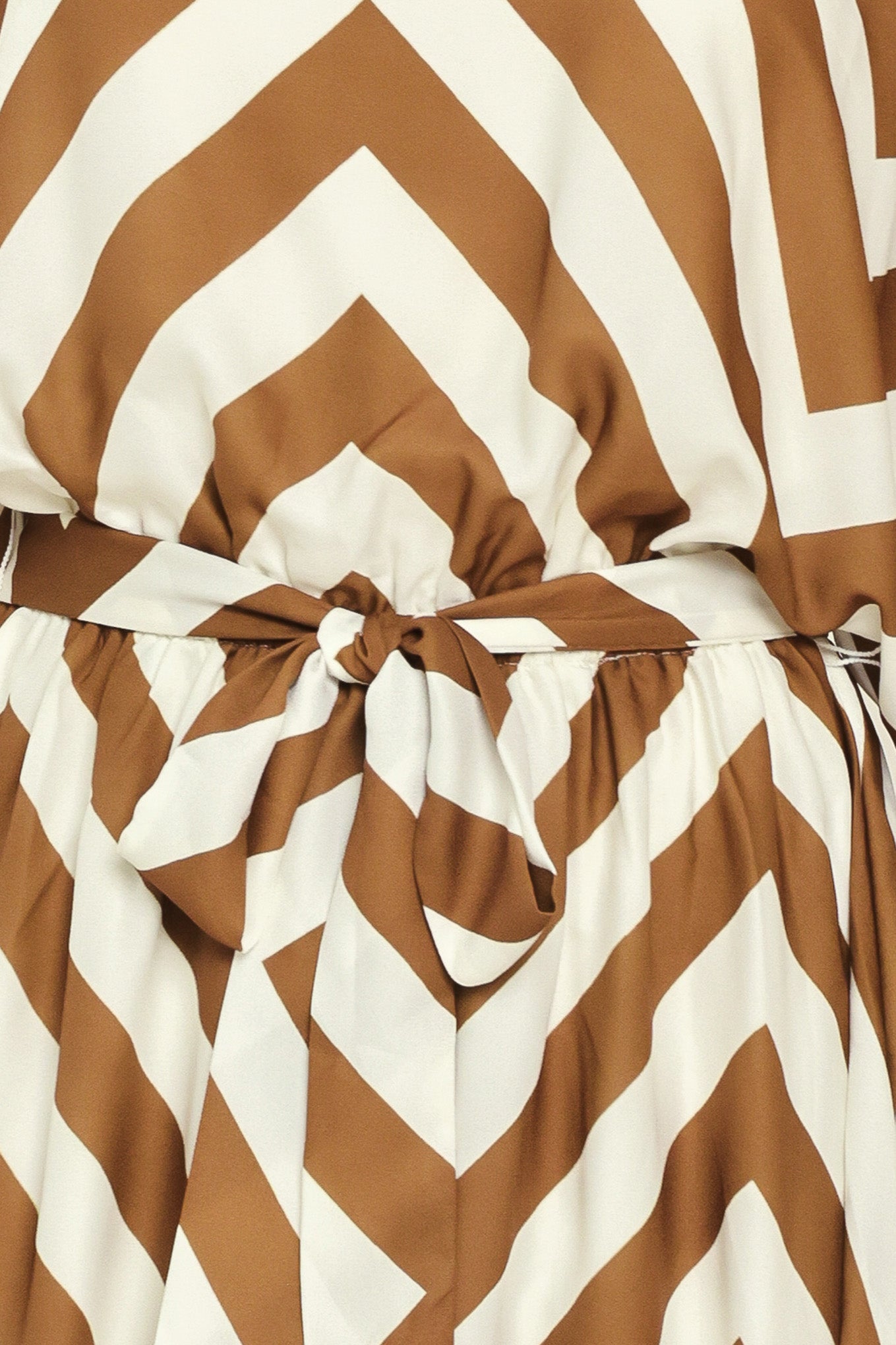 A woman modeling a long-sleeve maxi dress with a bold brown and ivory chevron pattern, featuring a tie waist belt | Flying Tomato
