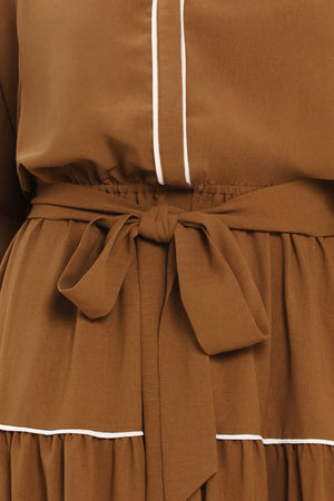 A woman wearing a brown long sleeve midi dress with white lined details, tiered skirt and self tie belt | Flying Tomato