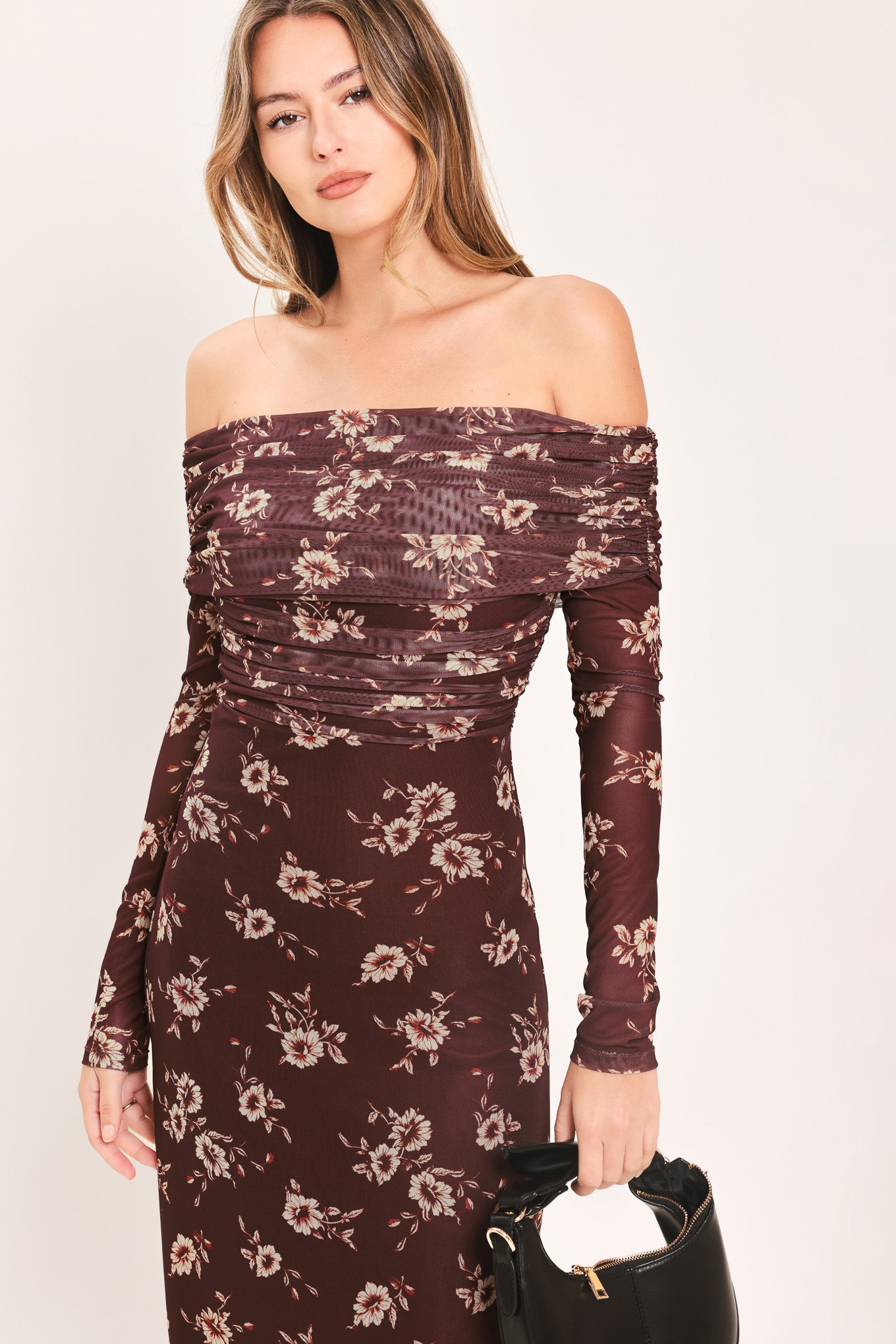 A woman modeling an off-the-shoulder long-sleeve maxi dress with a dark brown base and a beige floral pattern | Flying Tomato