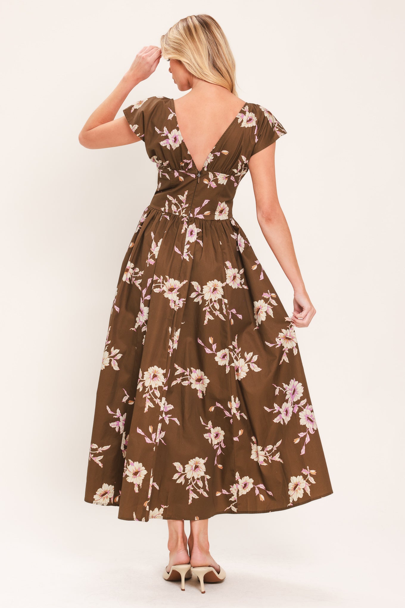 A woman wearing a brown midi dress with a pink and beige floral print, featuring cap sleeves, a deep V-neckline, and side pockets | Flying Tomato