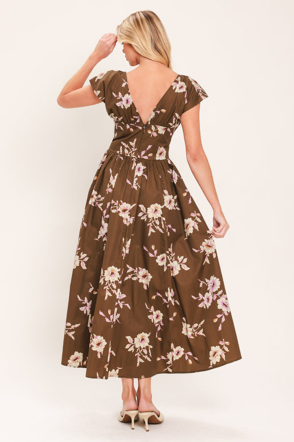 A woman wearing a brown midi dress with a pink and beige floral print, featuring cap sleeves, a deep V-neckline, and side pockets | Flying Tomato