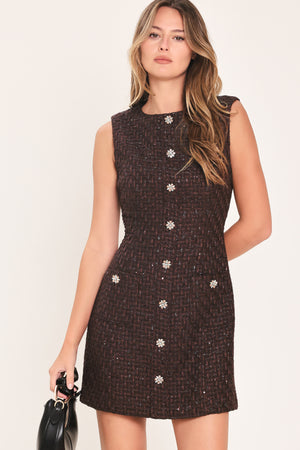 A woman modeling a sleeveless brown tweed mini dress with decorative silver floral embellishments down the front | Flying Tomato