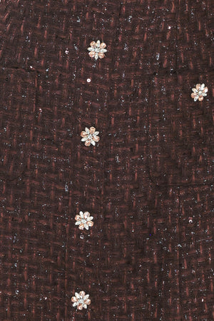 A woman modeling a sleeveless brown tweed mini dress with decorative silver floral embellishments down the front | Flying Tomato