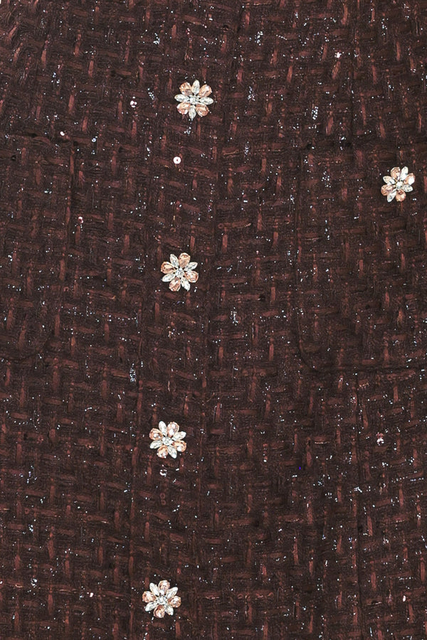 A woman modeling a sleeveless brown tweed mini dress with decorative silver floral embellishments down the front | Flying Tomato