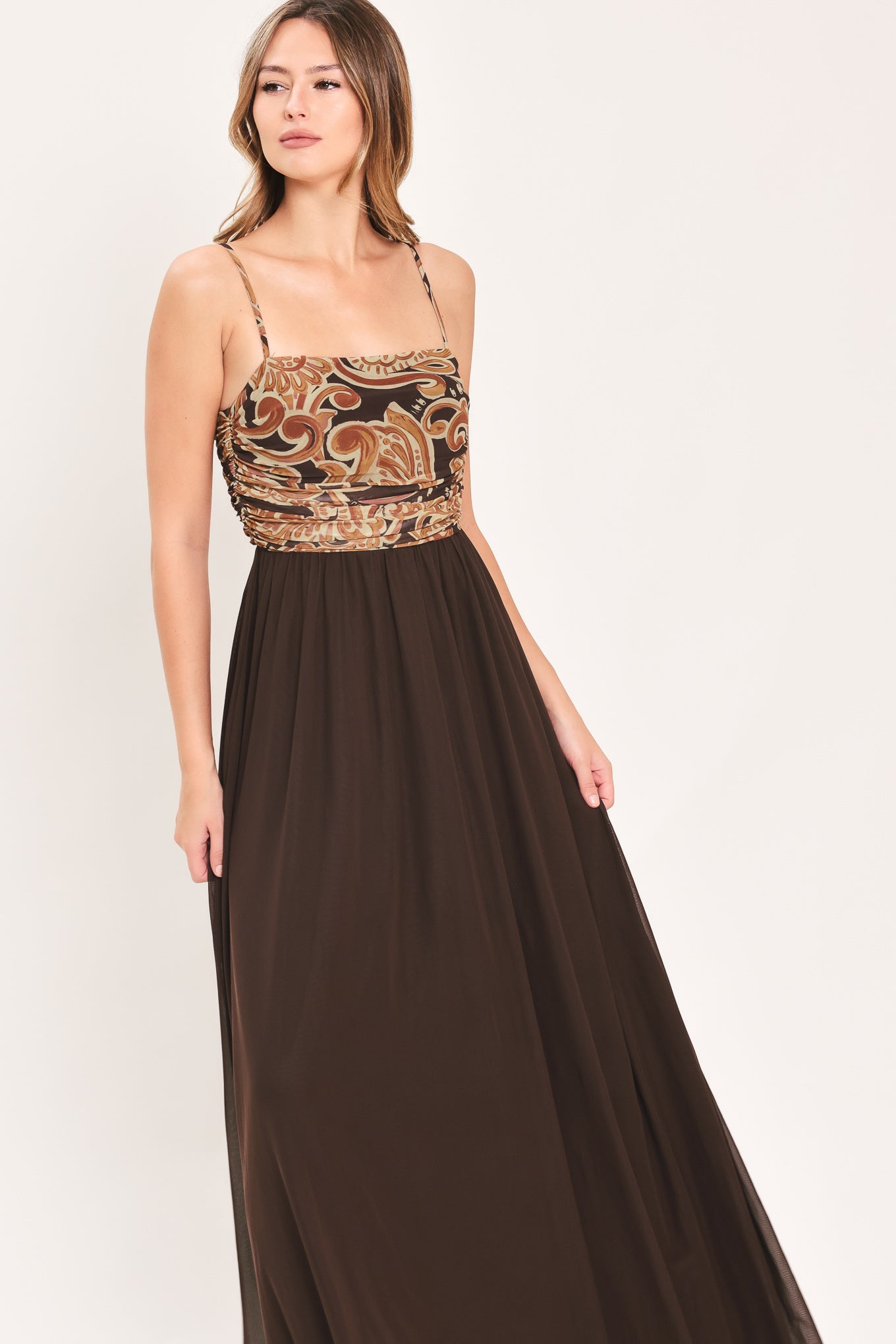A woman modeling a long brown maxi dress with a patterned bodice and flowing power mesh skirt | Flying Tomato