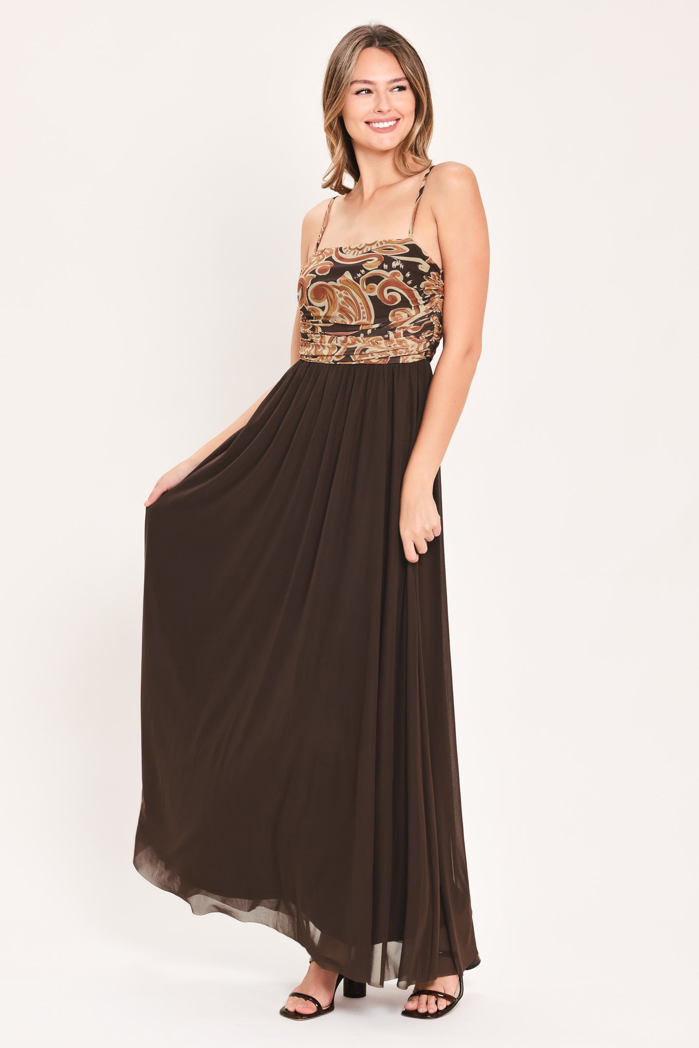 A woman modeling a long brown maxi dress with a patterned bodice and flowing power mesh skirt | Flying Tomato