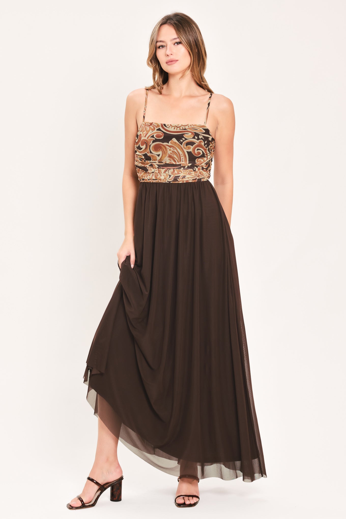 A woman modeling a long brown maxi dress with a patterned bodice and flowing power mesh skirt | Flying Tomato
