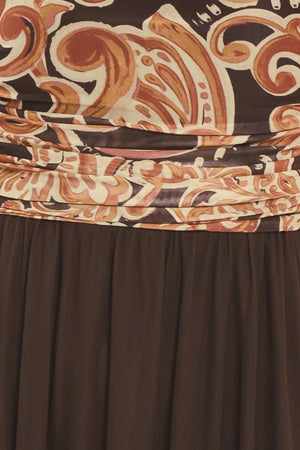 A woman modeling a long brown maxi dress with a patterned bodice and flowing power mesh skirt | Flying Tomato