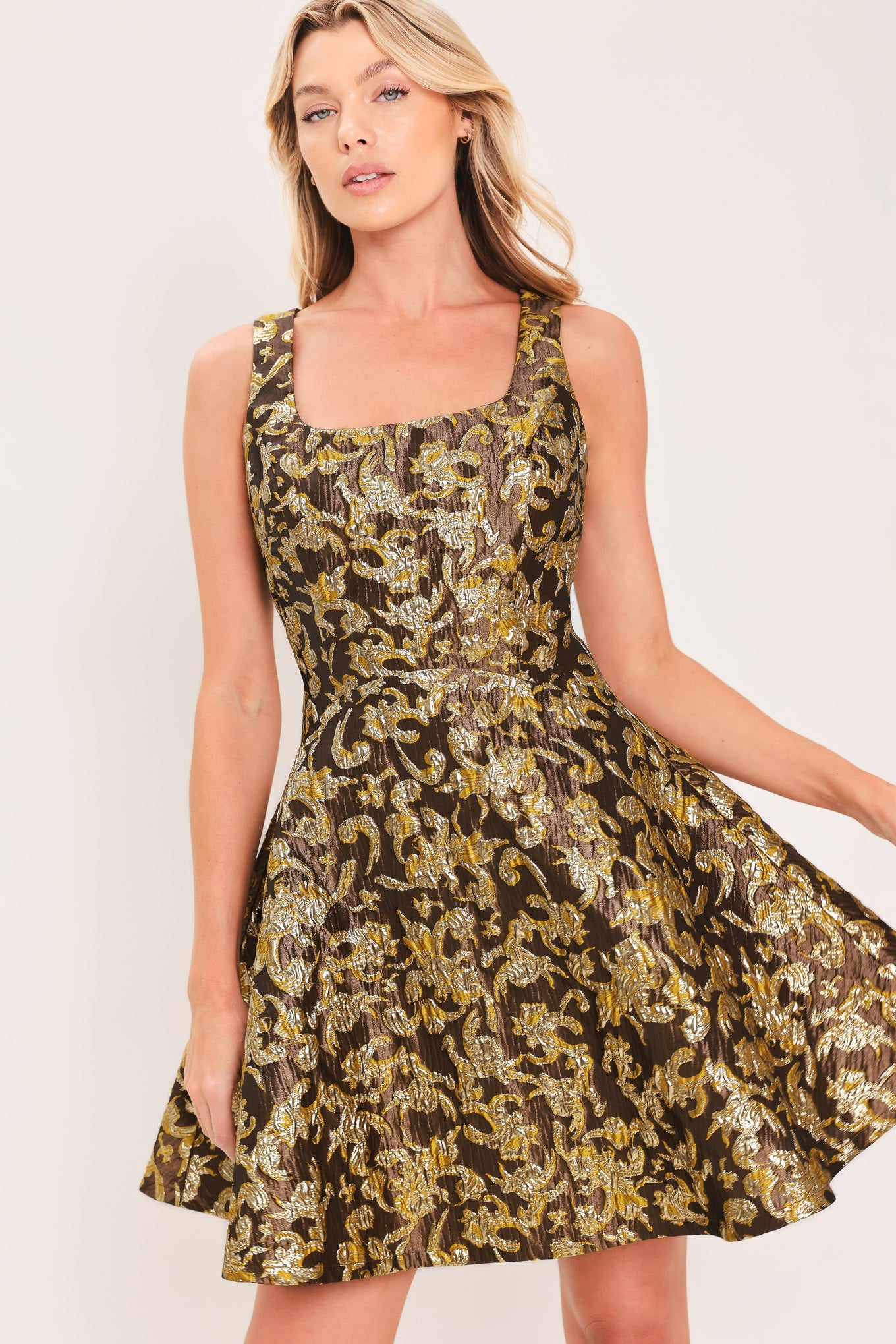 A woman modeling a sleeveless fit-and-flare dress with a brown, gold, and beige floral jacquard pattern | Flying Tomato