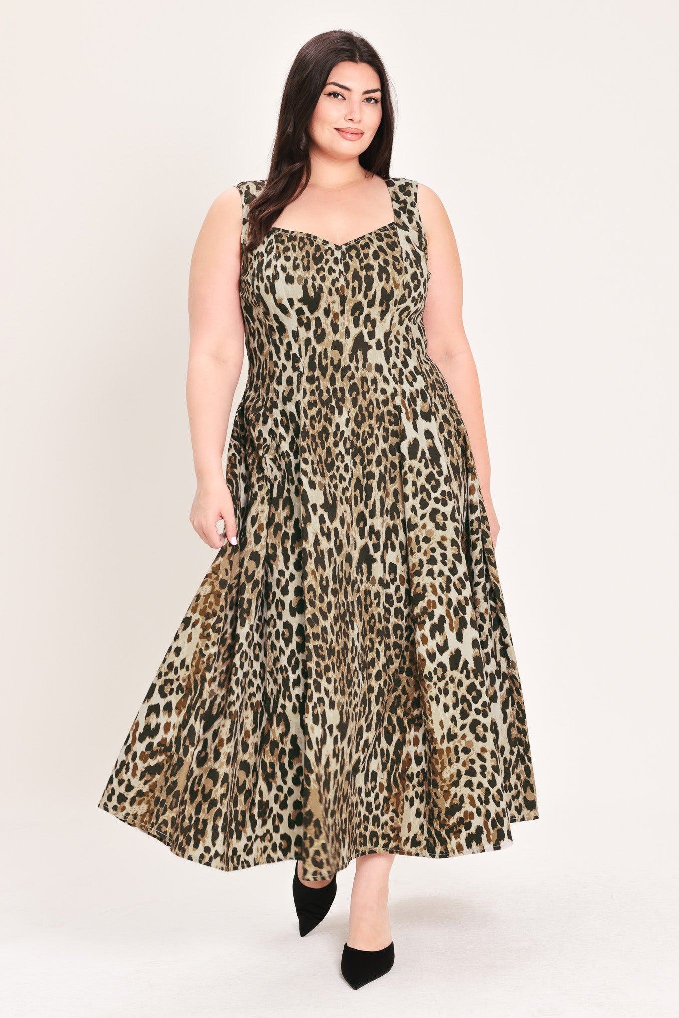 A woman modeling a sleeveless leopard-print midi dress with a structured bodice and flared skirt, paired with black pointed-toe heels, against a plain light background | FREEMARKET Curve