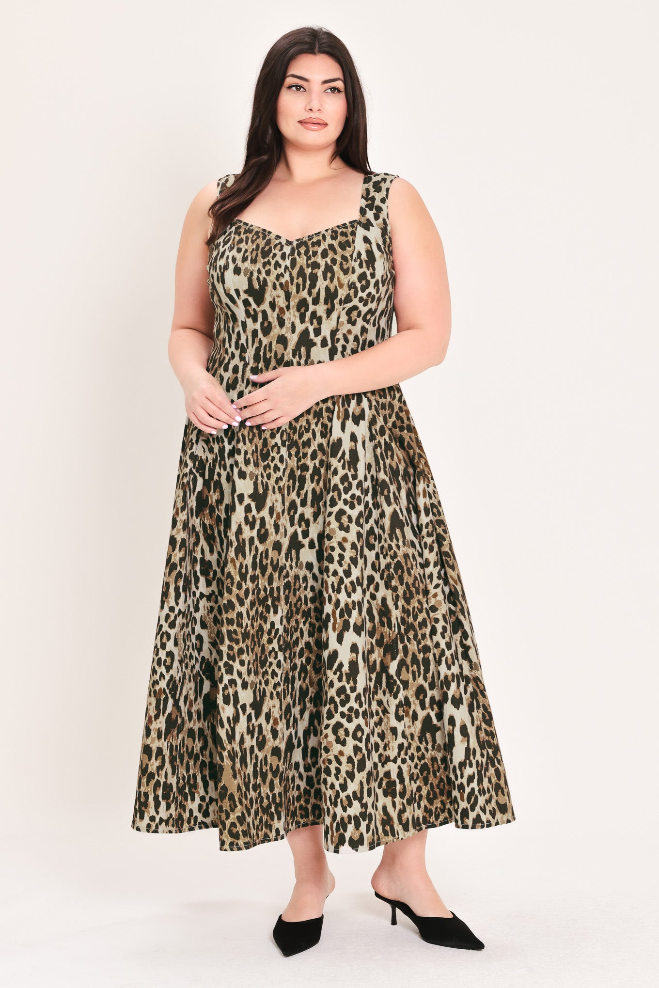 A woman modeling a sleeveless leopard-print midi dress with a structured bodice and flared skirt, paired with black pointed-toe heels, against a plain light background | FREEMARKET Curve