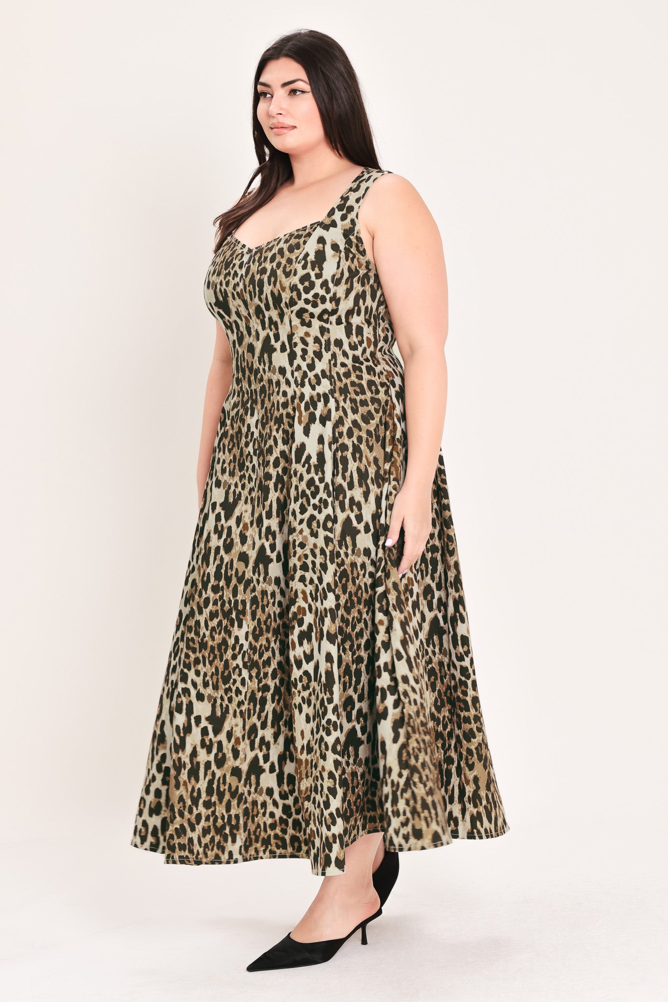 A woman modeling a sleeveless leopard-print midi dress with a structured bodice and flared skirt, paired with black pointed-toe heels, against a plain light background | FREEMARKET Curve