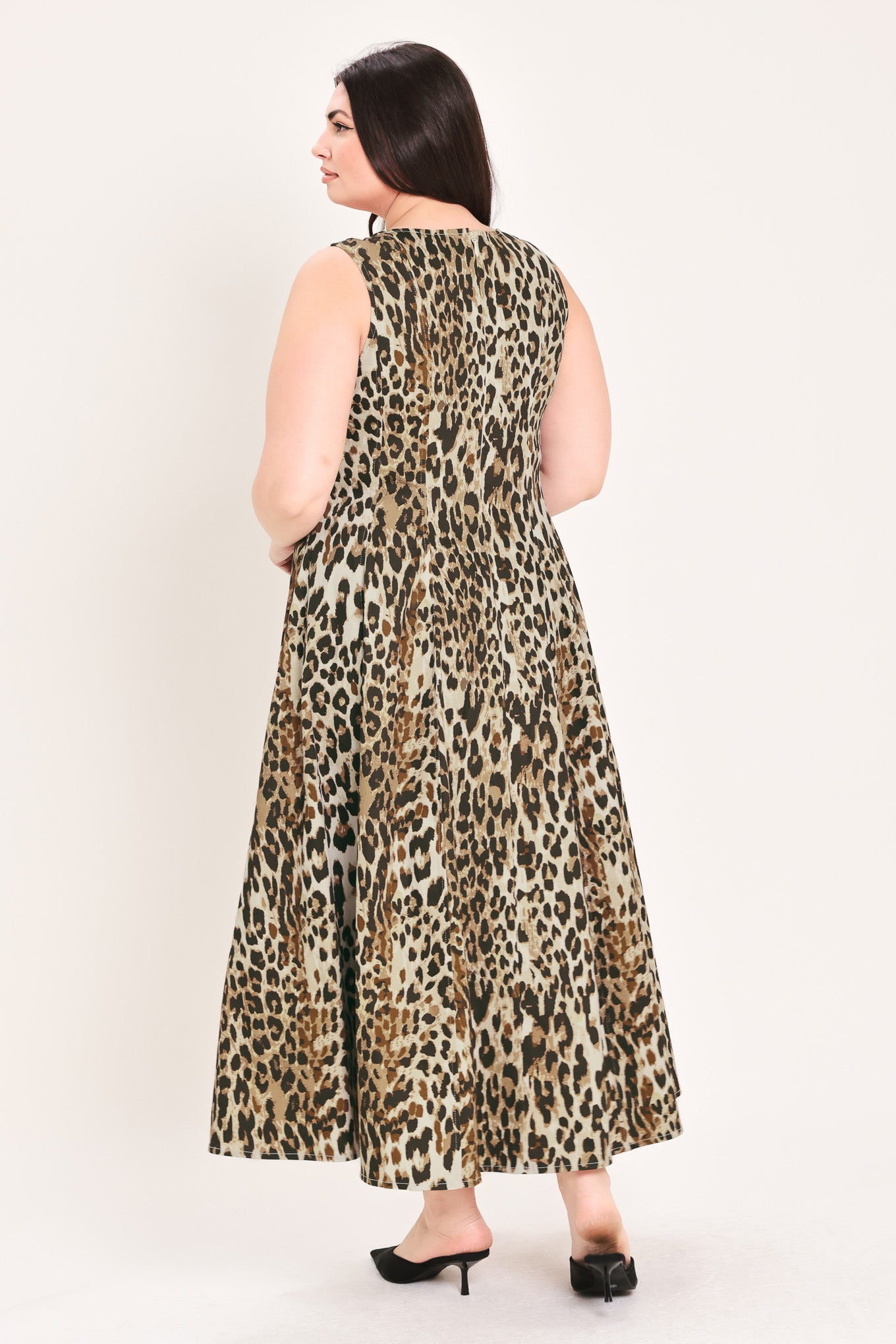A woman modeling a sleeveless leopard-print midi dress with a structured bodice and flared skirt, paired with black pointed-toe heels, against a plain light background | FREEMARKET Curve