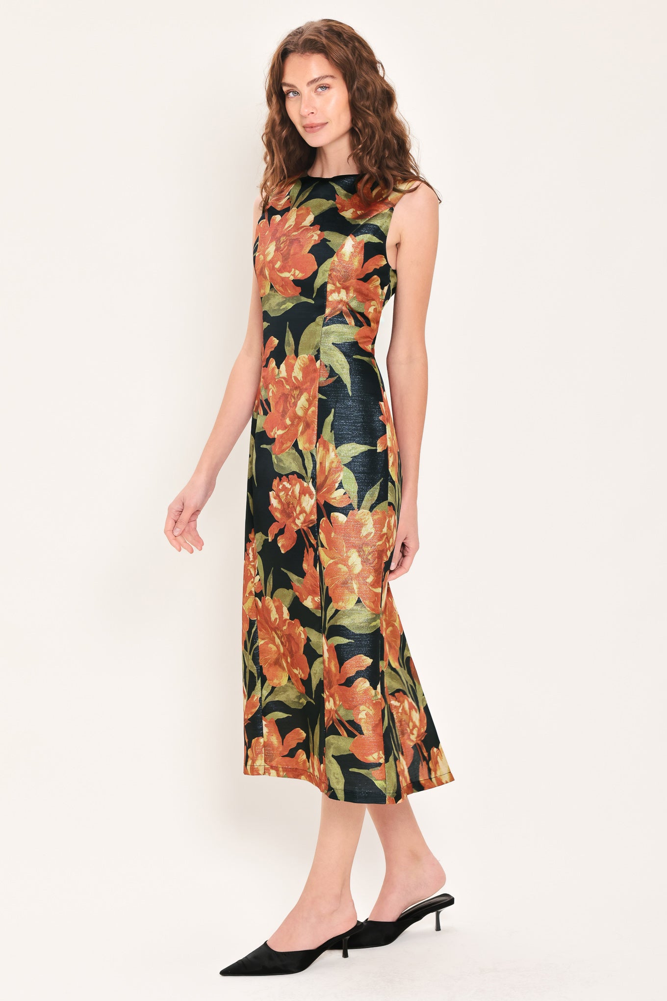 Woman wearing a sleeveless black midi sheath dress with orange flowers and green leaves printed | Flying Tomato