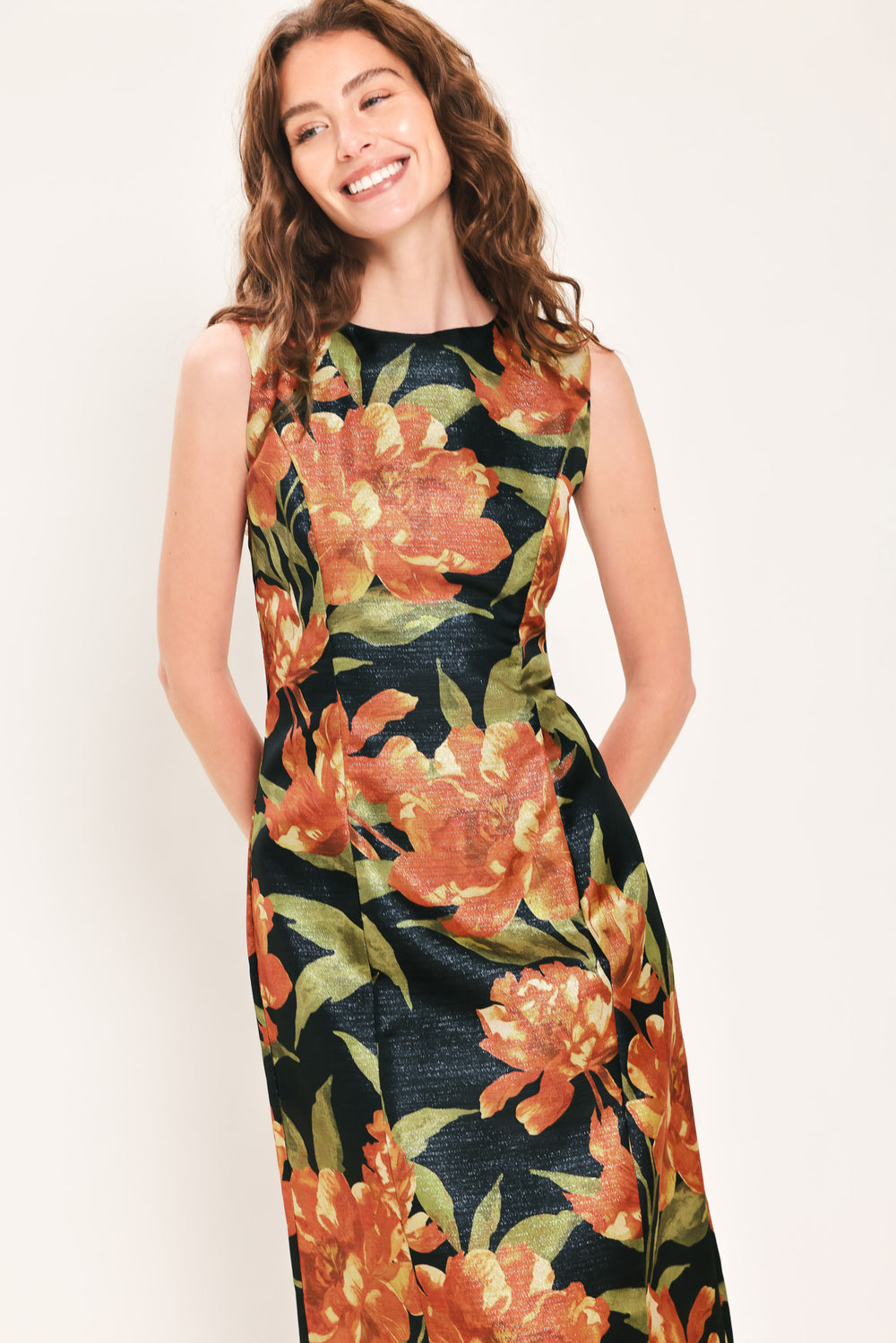 Woman wearing a sleeveless black midi sheath dress with orange flowers and green leaves printed | Flying Tomato