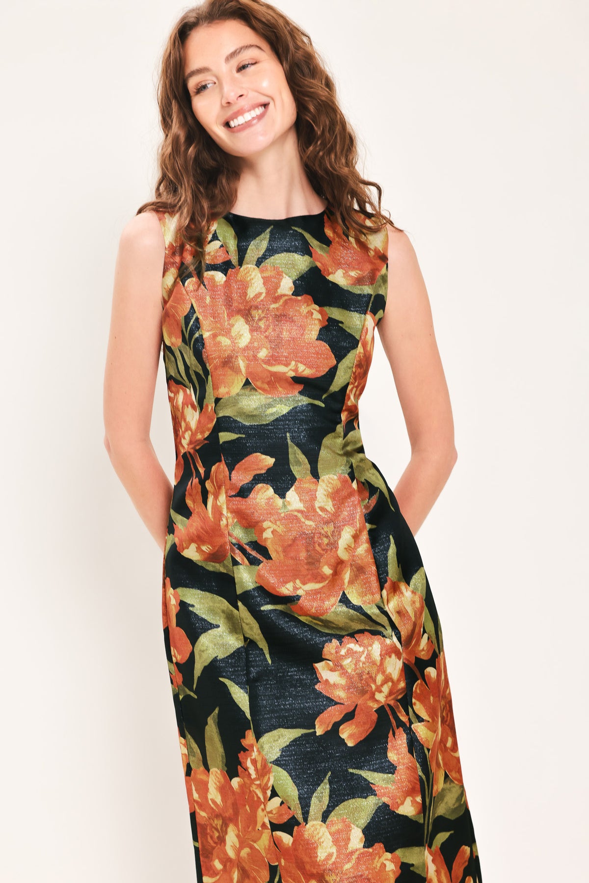 Woman wearing a sleeveless black midi sheath dress with orange flowers and green leaves printed | Flying Tomato