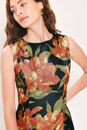 Woman wearing a sleeveless black midi sheath dress with orange flowers and green leaves printed | Flying Tomato