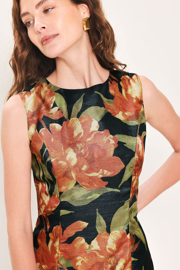 Woman wearing a sleeveless black midi sheath dress with orange flowers and green leaves printed | Flying Tomato
