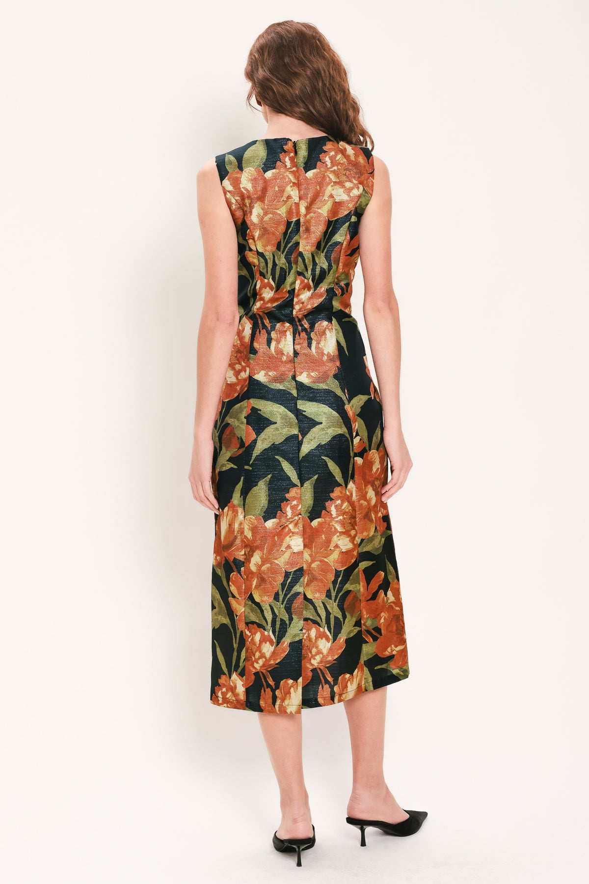 Woman wearing a sleeveless black midi sheath dress with orange flowers and green leaves printed | Flying Tomato