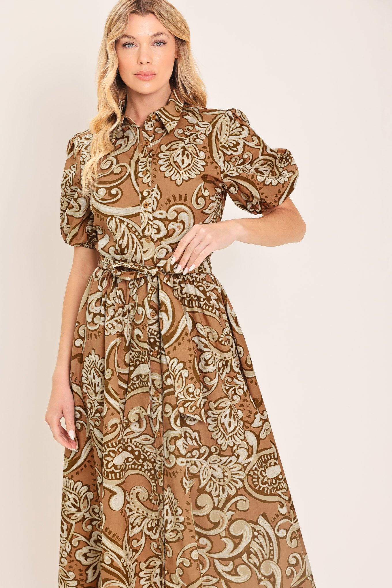 Woman wearing a patterned taupe and brown midi dress featuring collar, short puff sleeve, front button down, self sash and full skirt | Flying Tomato