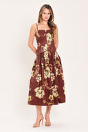 A woman modeling a sleeveless midi dress with a burgundy base and a large beige floral print | Flying Tomato