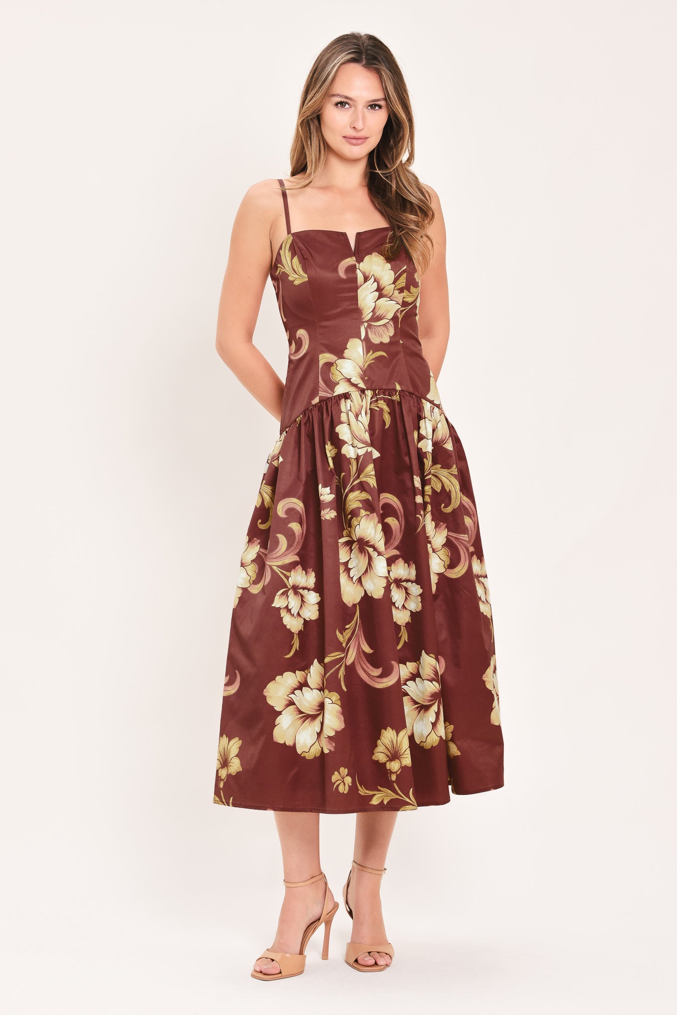 A woman modeling a sleeveless midi dress with a burgundy base and a large beige floral print | Flying Tomato