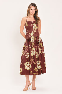 A woman modeling a sleeveless midi dress with a burgundy base and a large beige floral print | Flying Tomato