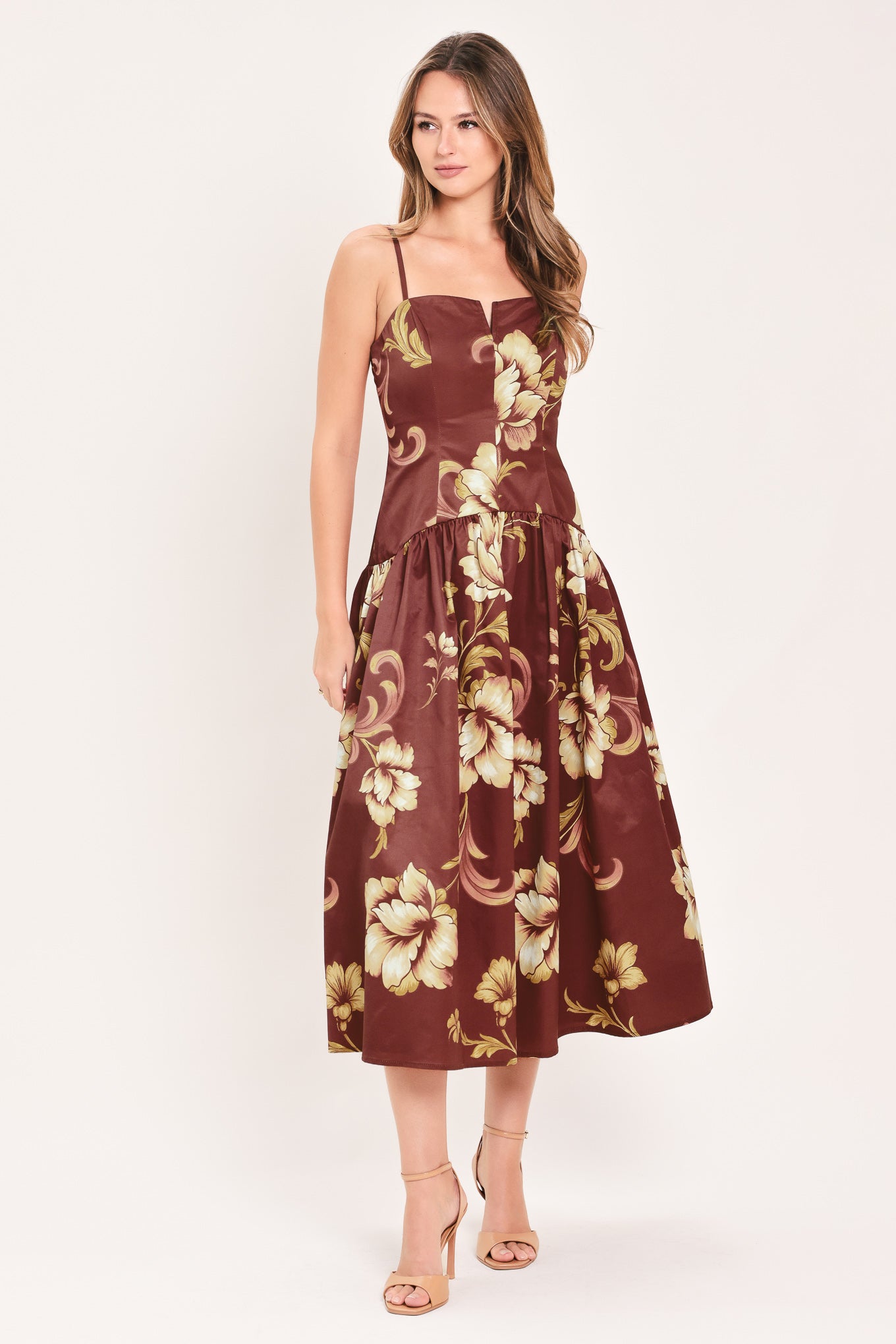 A woman modeling a sleeveless midi dress with a burgundy base and a large beige floral print | Flying Tomato