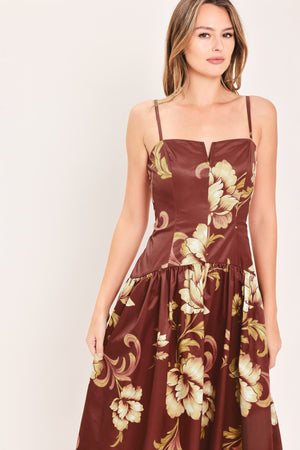 A woman modeling a sleeveless midi dress with a burgundy base and a large beige floral print | Flying Tomato